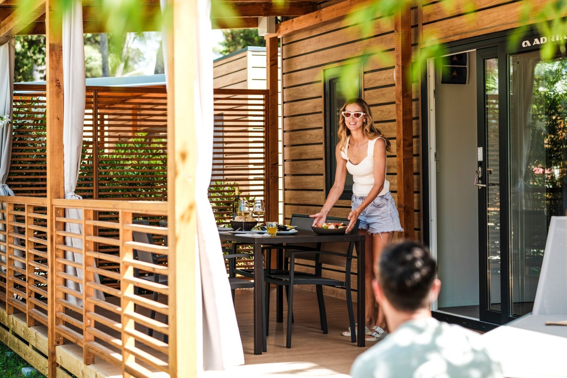 Zaton Holiday Resort Gość przygotowujący posiłek na tarasie domku campingowego otoczonego zielenią