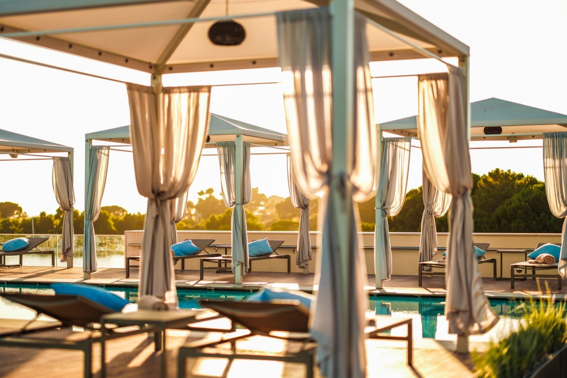 Zadaszone leżanki z zasłonami przy basenie w Ventula Lounge w Zaton Holiday Resort